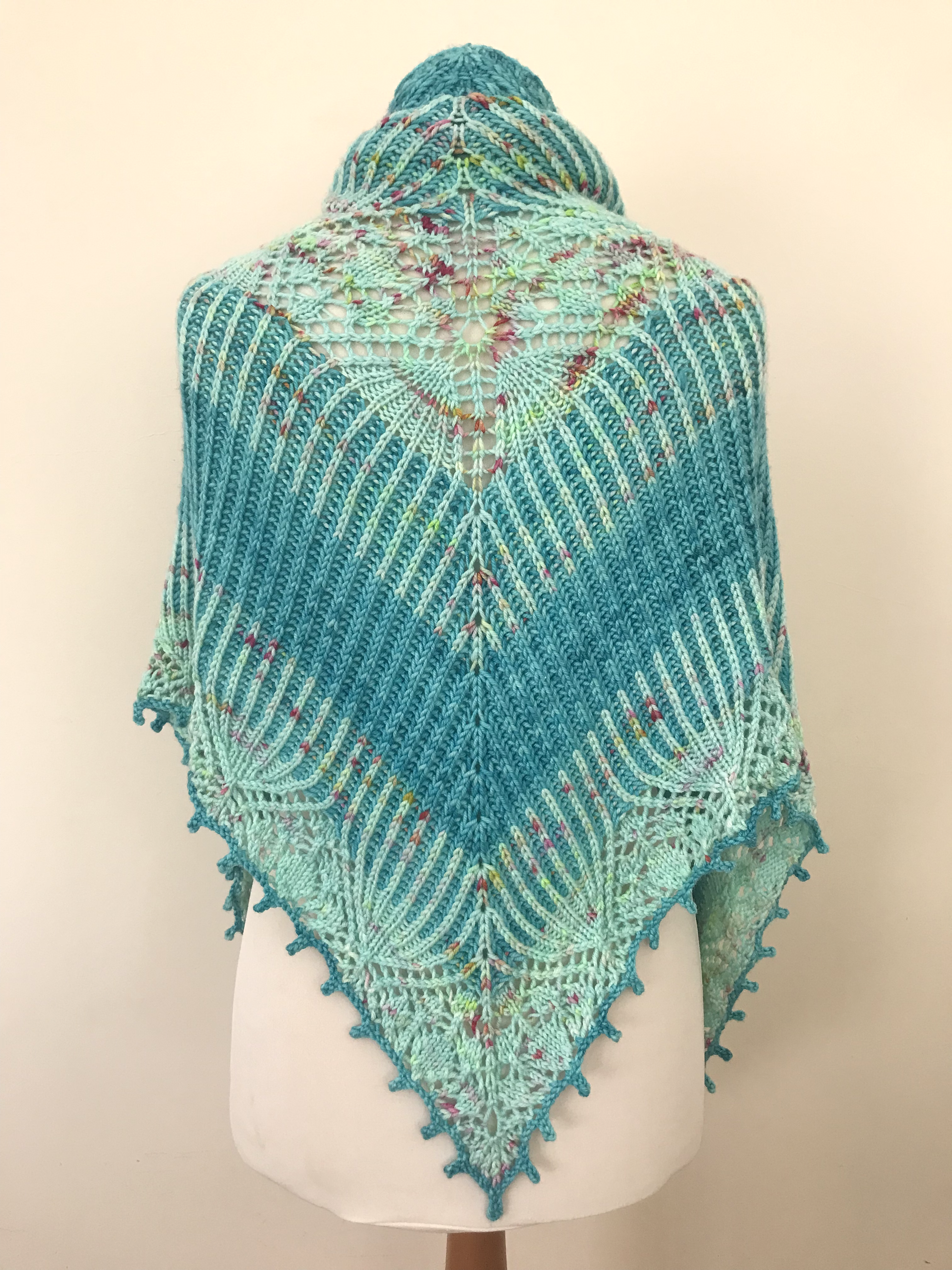 Brioche and lace shawl draped over the back of a mannequin so that the various sections are visible